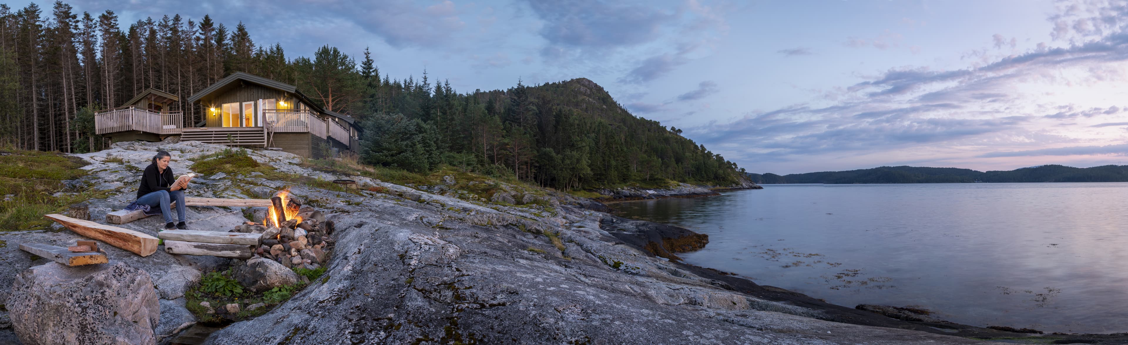fosnes,trondelag, norway panoramic view woman reading near campfire in norway