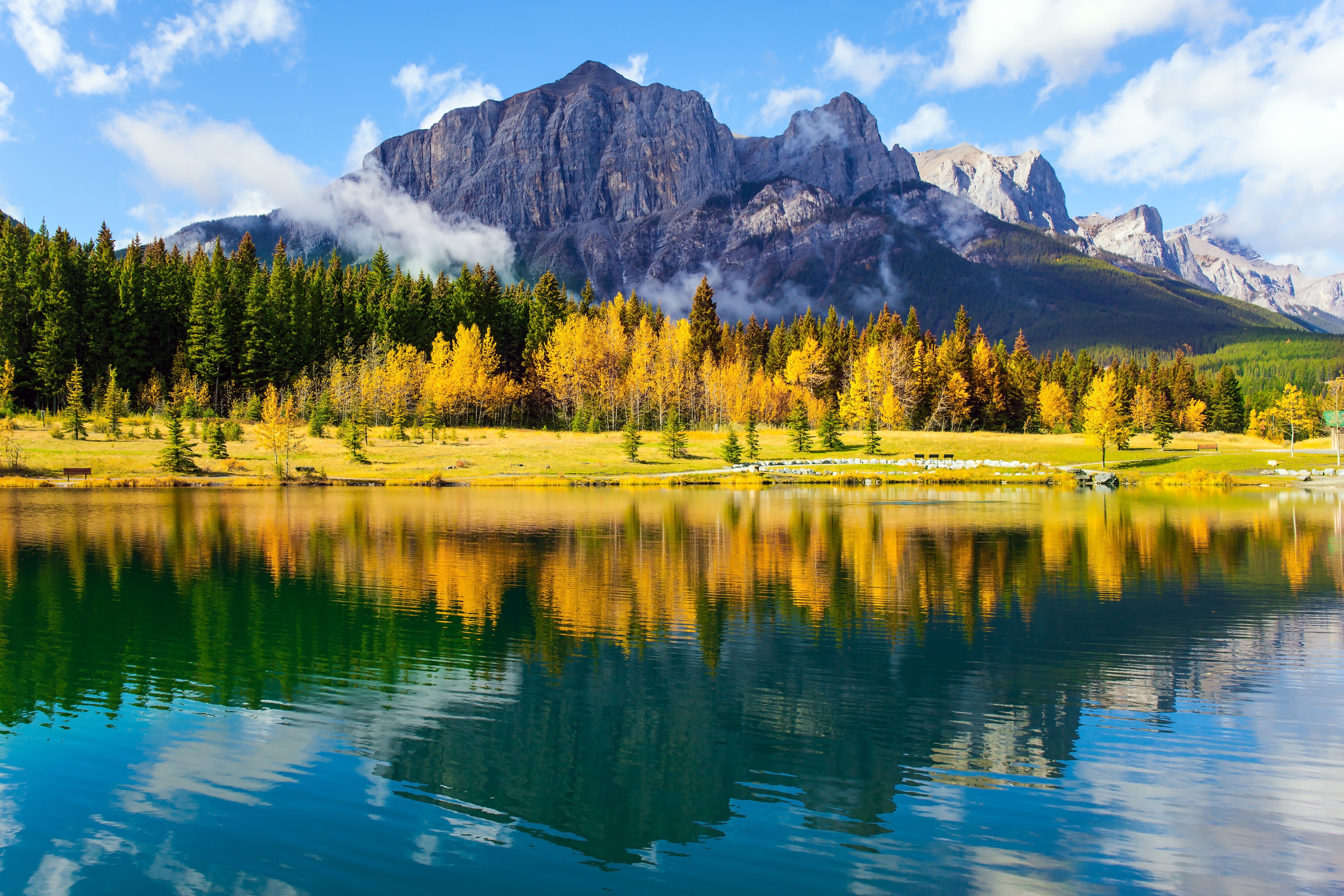 The Canadian Rockies. Bright autumn forest is reflected in the smooth water of the lake. The city of Canmore is  in Canadian Banff National Park. The concept of active, ecological and photo tourism. Banff City Attraction 08