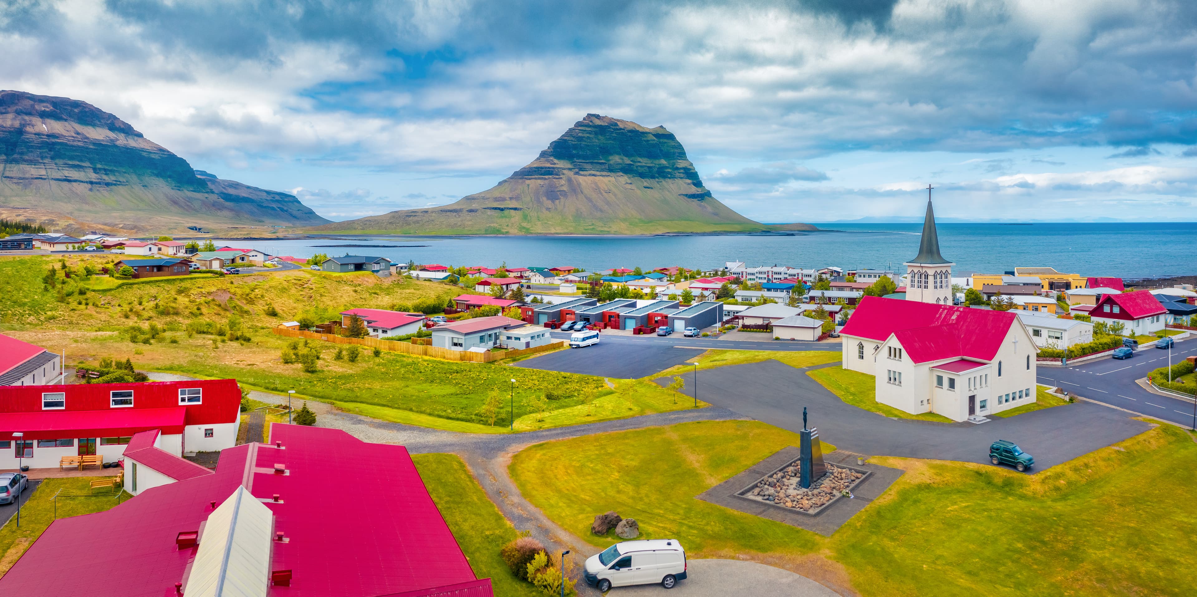 Aerial landscape photography. Splendid summer view from flying drone of empty street of Grundarfjordur town with Kirkjufell Mountain on background, Iceland, Europe. Aerial landscape photography. Splendid summer view from flying drone of empty street of Grundarfjordur town with Kirkjufell Mountain on background, Iceland, Europe.