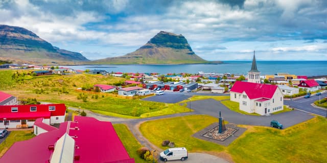 Aerial landscape photography. Splendid summer view from flying drone of empty street of Grundarfjordur town with Kirkjufell Mountain on background, Iceland, Europe. Aerial landscape photography. Splendid summer view from flying drone of empty street of Grundarfjordur town with Kirkjufell Mountain on background, Iceland, Europe.