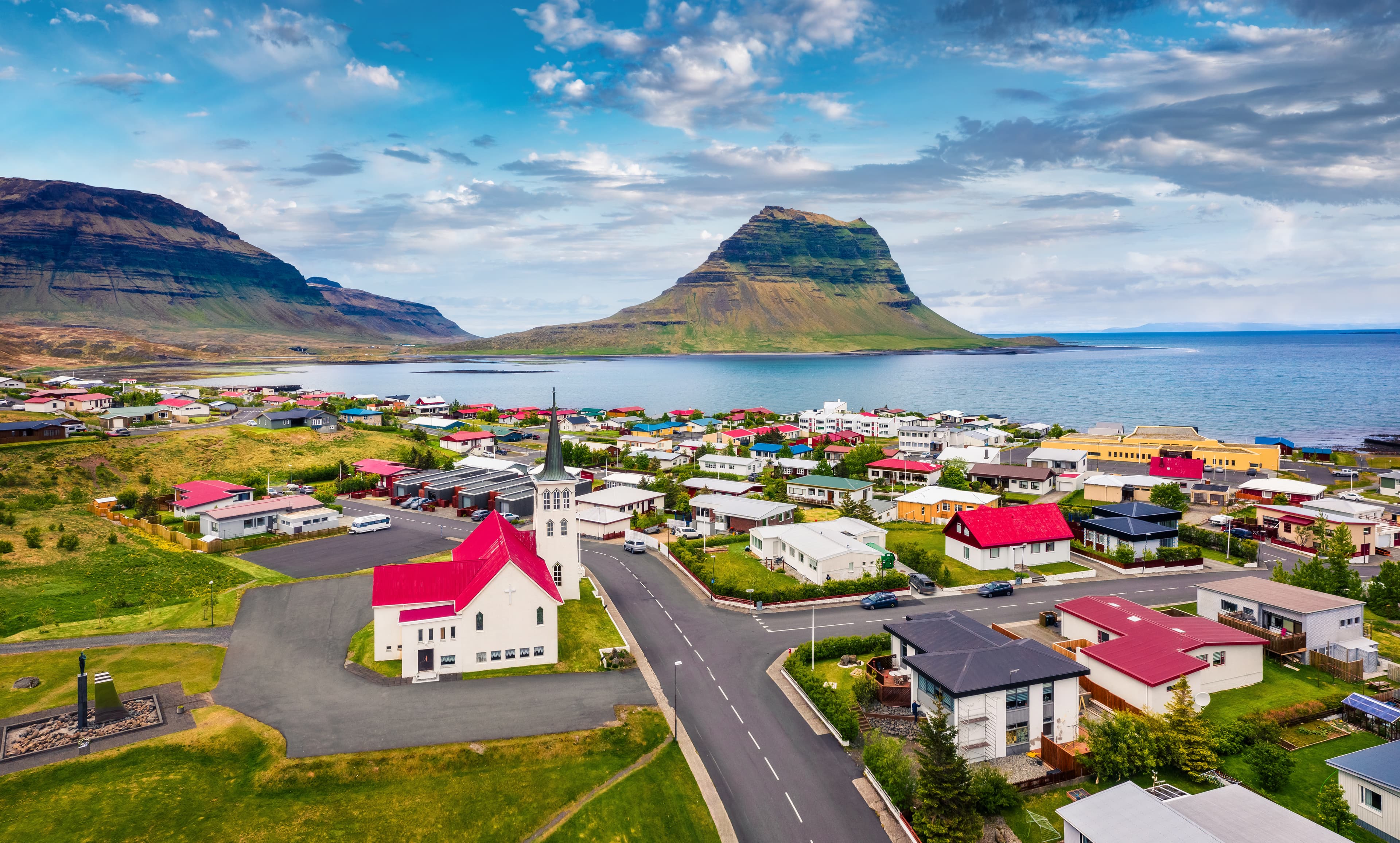 View from flying drone. Splendid morning cityscape of Grundarfjordur town with Kirkjufell Mountain on background. Aerial view of Grundarfjordur Church, Iceland, Europe. Traveling concept background. View from flying drone. Splendid morning cityscape of Grundarfjordur town with Kirkjufell Mountain on background. Aerial view of Grundarfjordur Church, Iceland, Europe. Traveling concept background.