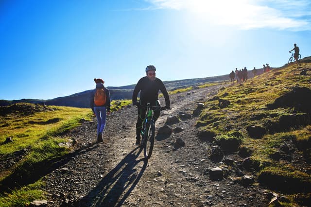 back view of woman traveler on a walk in the Valley of the river of Hveragerdi Iceland, the cyclist bikes down the slope. Hiking Tour of Reykjadalur Hot Springs woman traveler on a walk in the Valley of the river of Hveragerdi Iceland, the cyclist bikes down the slope