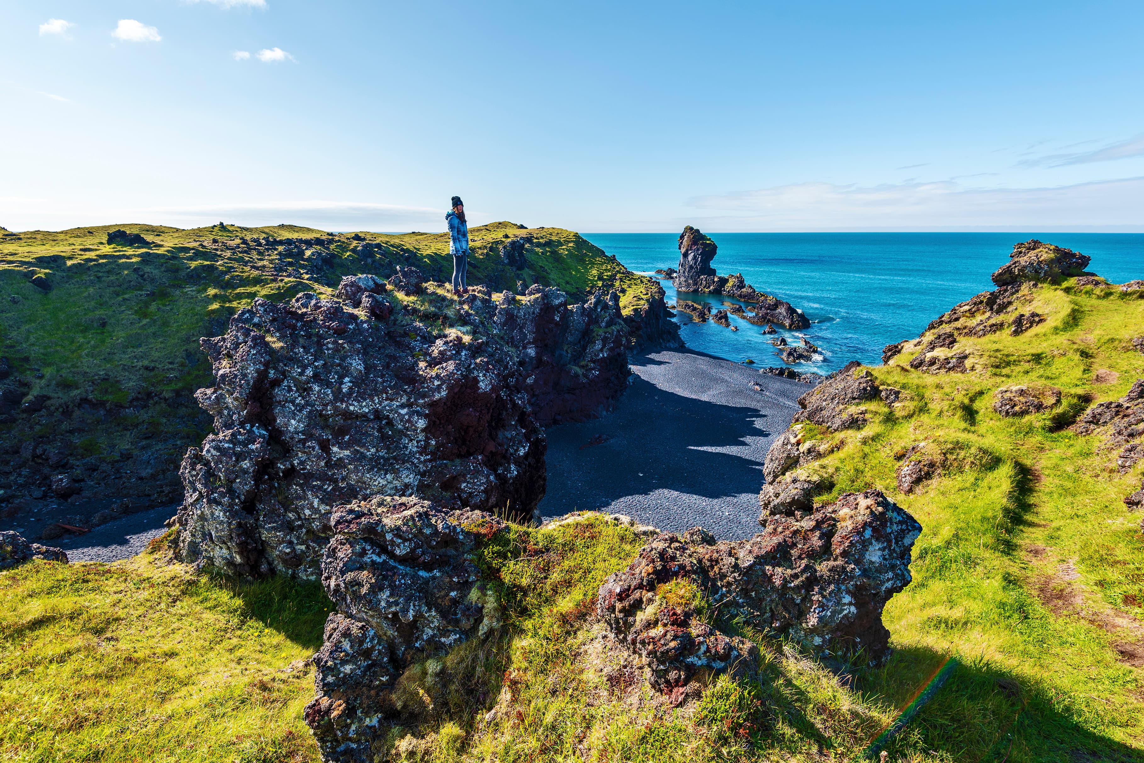 Girl Teenagers staying in the top of the lava rock observing the landscape of Djupalonssandur beach in Icelandic Snaefellsjokull National Park. Snaefellsnes peninsula in Western Iceland. girl-lava-rock-djupalonssandur-beach in Icelandic-snaefellsjokull