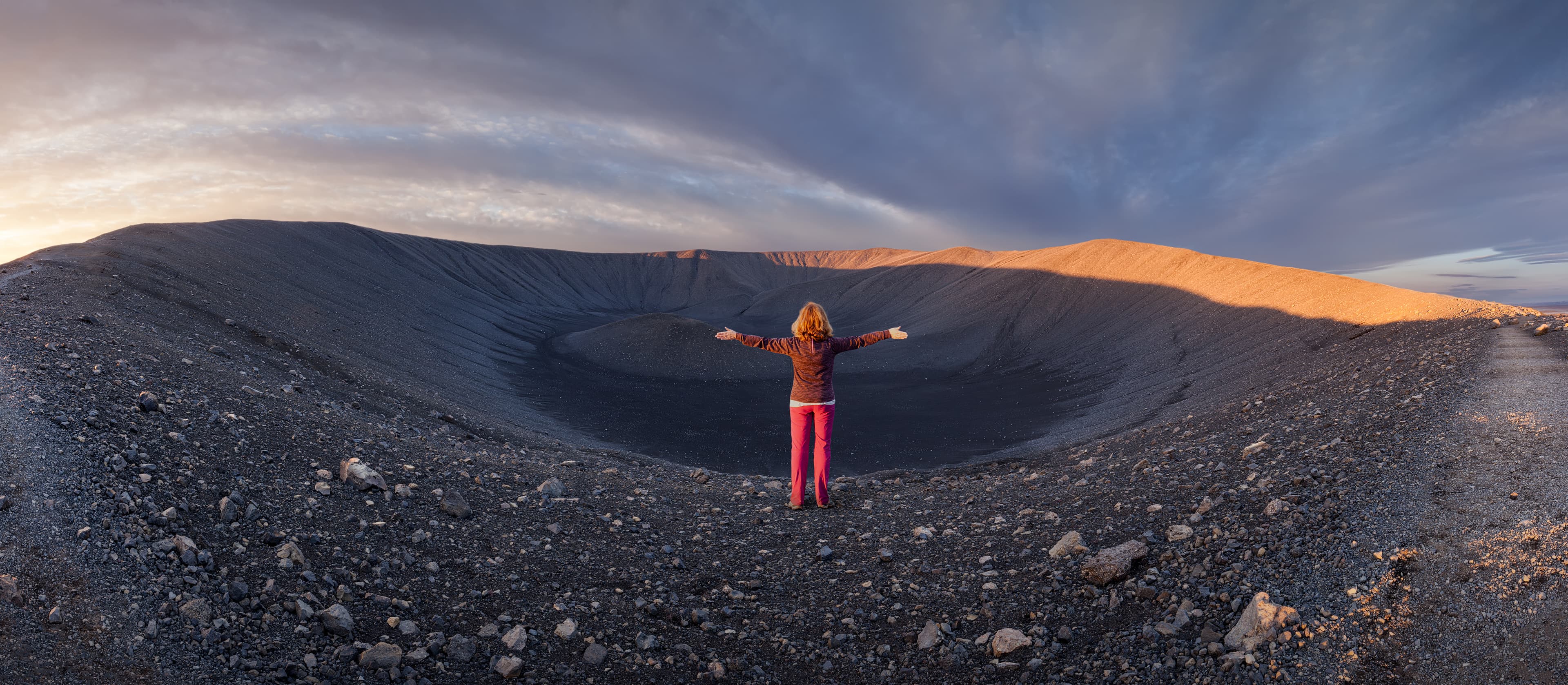 Iceland landscape photo of girl who proudly standing with his arms raised in front of huge volcano crater at sunrise. hverfjall-volcano-northern-iceland-myvatn
