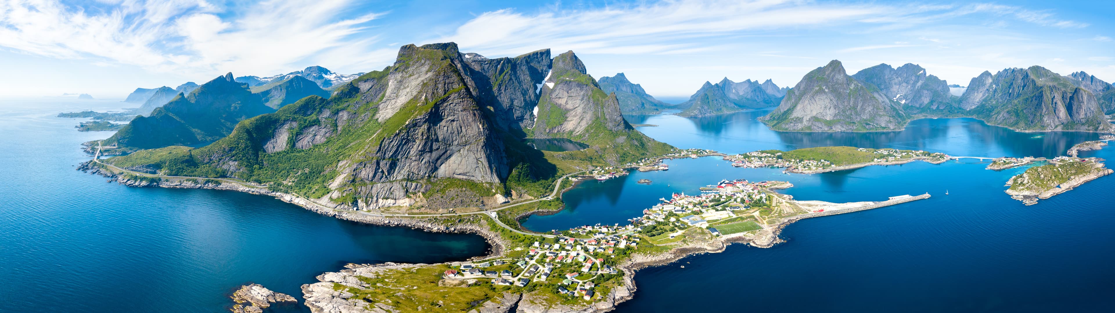 Aerial panoramic view of Reine traditional fishing village in the Lofoten archipelago in northen Norway with blue sea and mountains during sunny arctic summer Aerial panoramic view of Reine, Lofoten, Norway, sunny arctic summer