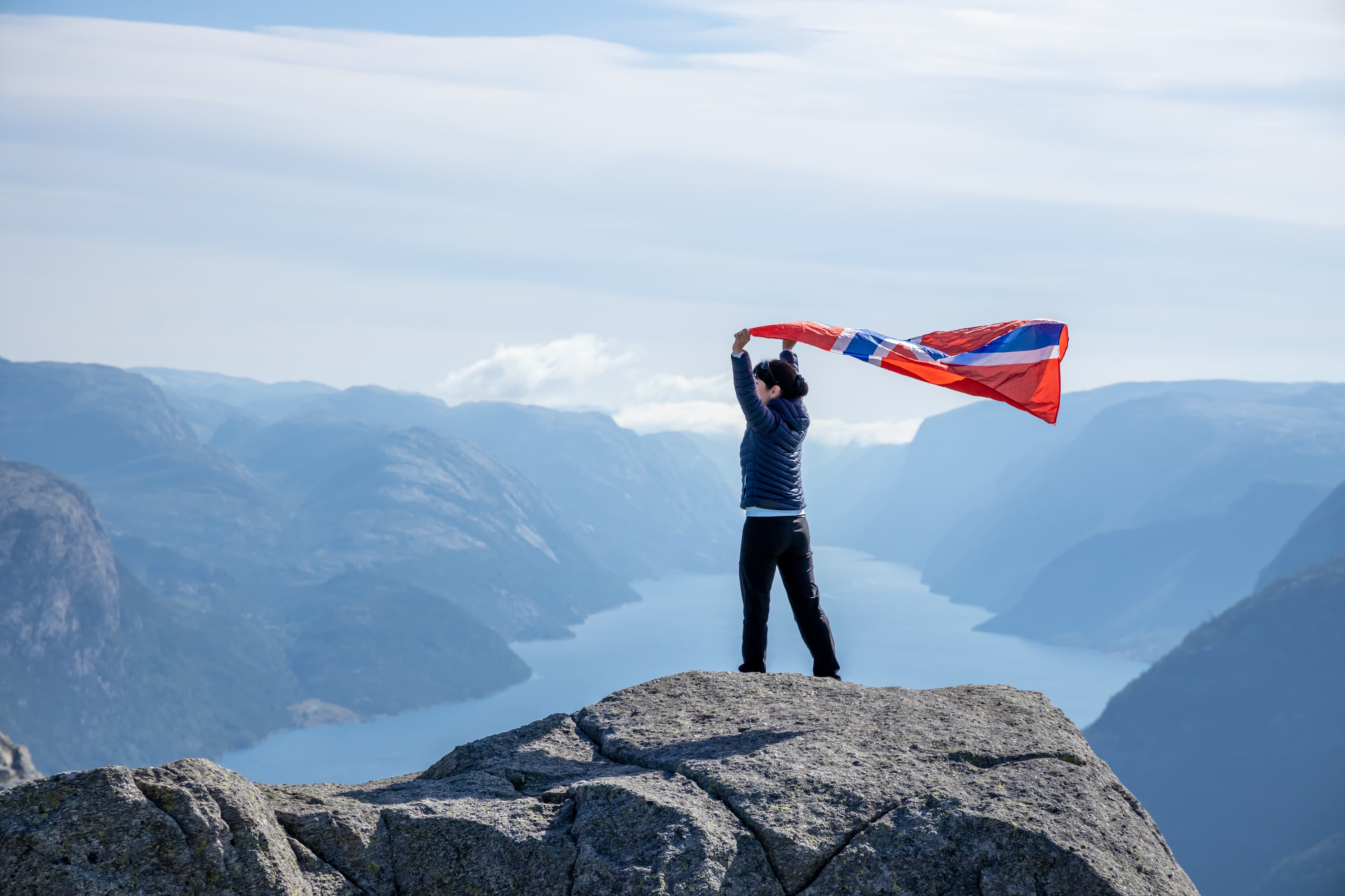 Woman with a waving flag of Norway on the background of nature Woman with a waving flag of Norway on the background of nature