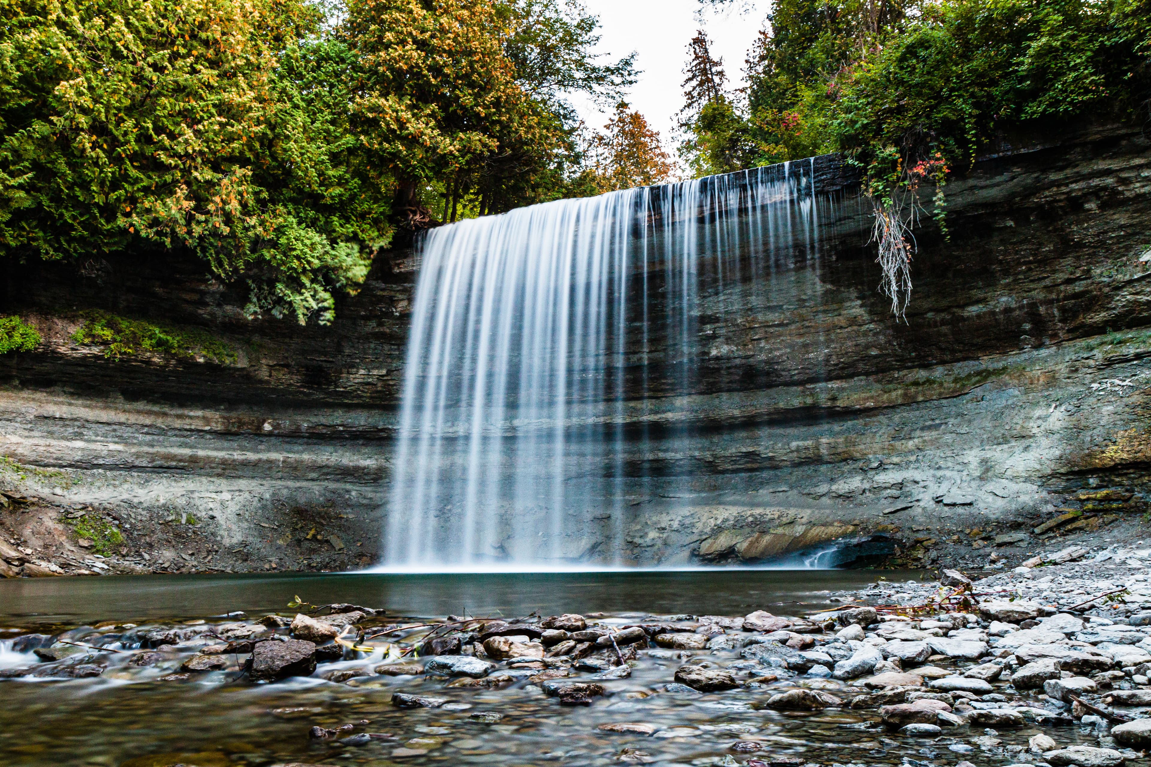 Stock Waterfall on Manitoulin Island in Ontario Canada at Sunset. Long time exposure of beautiful Bridal Veil Falls on Manitoulin Island surrounded bei trees and lake and ability to walk behind the falls.